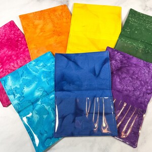 May include: Seven fabric pouches in various colors, including pink, orange, yellow, green, blue, and purple. The pouches have a clear plastic window on the front.