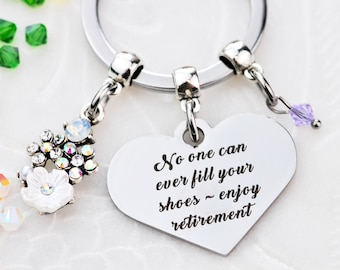 May include: Silver heart-shaped keychain with the inscription "No one can ever fill your shoes - enjoy retirement". The keychain has a flower charm and a small purple crystal charm.