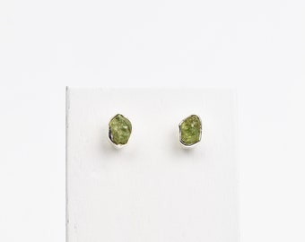 May include: A pair of silver earrings with small, rough, green gemstones.