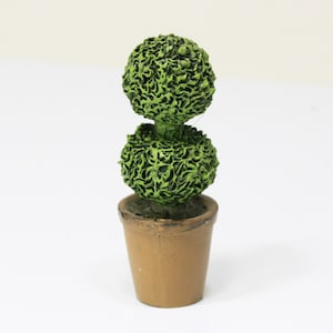 May include: A miniature topiary plant in a brown pot. The plant has two spherical, textured, green sections stacked on top of each other. The pot is a light brown color and has a simple, classic design.