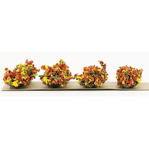 May include: Four colorful miniature tree clusters in shades of red, orange, yellow, and green, arranged on a brown rectangular base. These decorative clusters are likely used for model scenery or craft projects.