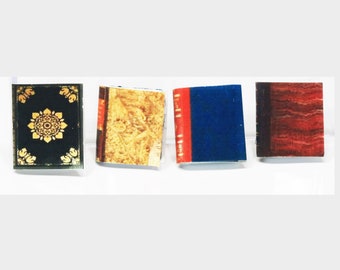 May include: Four miniature books with different covers. One has a black cover with a gold floral design. Another has a tan cover with a floral pattern. The third has a blue cover with a red spine. The last has a red and brown cover.