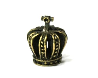 May include: A small, antique-style crown charm in a bronze color. The crown has a detailed design with vertical bars and rounded accents. The charm is likely made of metal and sits on a white background.