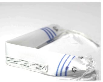 May include: White fabric with blue stripes and a decorative stitched edge. The fabric appears to be folded over, with a clear plastic string attached. The item has a small embroidered design.