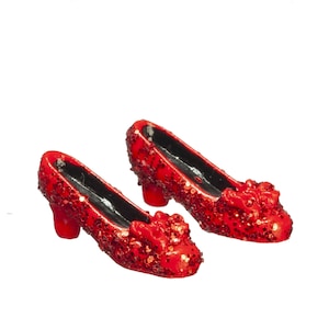 May include: A pair of red sequined pumps with a small heel. The shoes have a rounded toe and a decorative bow on the vamp. The interior of the shoe is black.