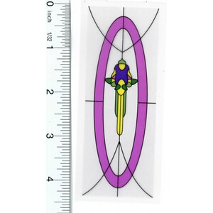 May include: A colorful sticker featuring a cyclist in a stylized design. The cyclist is depicted in purple, yellow, and green, set against a purple oval and black lines. The sticker is approximately 4 inches in height.