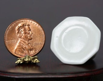May include: A miniature white ceramic plate with an octagonal shape, next to a 2014 penny. The penny is propped up on a small gold-colored stand. The plate is approximately 1 inch in diameter.