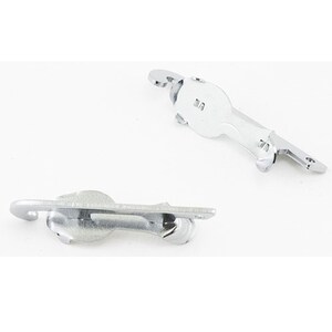 May include: Two shiny, silver-colored metal latches. Each latch has a curved hook, a rounded body, and a flat, rectangular base with screw holes. The latches are designed for securing doors or other closures.