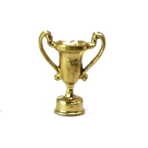 May include: A small, gold-colored trophy with two curved handles and a pedestal base. The trophy is made of a shiny, metallic material and is set against a white background. It is a miniature version of a classic award.