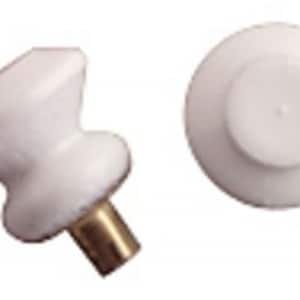 May include: Two white ceramic cabinet knobs with a brass stem. One knob is viewed from the side, showing its rounded shape, while the other is viewed from above, revealing its circular design. These knobs are suitable for furniture.