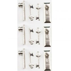 May include: A collection of small, silver-colored metal charms. The charms include keys, clasps, and decorative elements. The keys have a classic skeleton key design. The clasps have a rectangular shape with a circular button. These charms are likely for jewelry making or crafting.