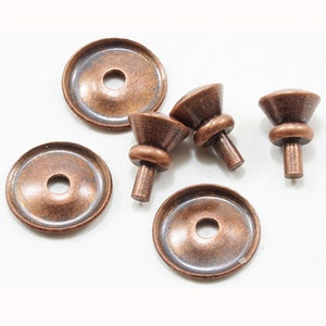 May include: A collection of antique copper-colored furniture hardware, including several decorative knobs and matching washers. The knobs have a rounded top and a cylindrical stem, while the washers are flat with a central hole.