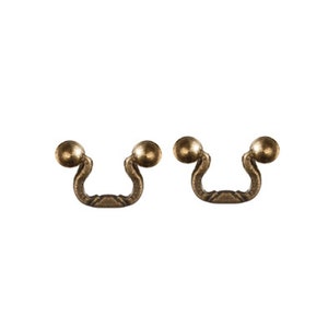 May include: Two antique bronze-colored drawer pulls. Each pull has a curved handle with a decorative center and a spherical knob on each end. These pulls are designed for furniture restoration or DIY projects.