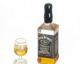 May include: A miniature Jack Daniel's whiskey bottle and a small glass of whiskey. The bottle has a black label with white text and a black cap. The glass is clear and contains a golden liquid.