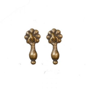 May include: Two antique brass drawer pulls. Each pull features a floral design at the top, a teardrop-shaped body, and a small round base. The pulls are made of a brass-colored metal and are set against a white background.