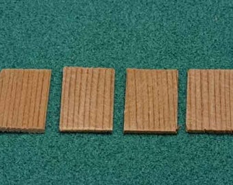 Op de afbeelding: Vier kleine, rechthoekige houten blokken met een lichtbruine kleur en verticale nerf zijn gerangschikt op een groene ondergrond. De blokken lijken uit hetzelfde stuk hout gesneden te zijn.