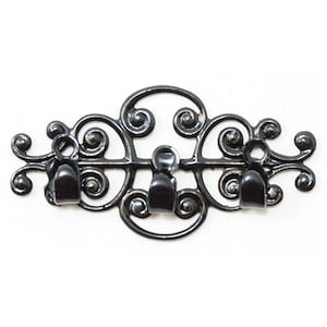 May include: Ornate black metal wall hook with three hooks. The decorative piece features a scrolling design with a central oval and curved accents. The hooks are positioned below the decorative elements.