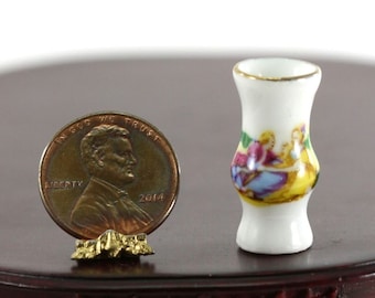 May include: A miniature white porcelain vase with a gold rim and a colorful scene of figures. The vase is next to a penny for scale. The vase is approximately 1 inch tall.