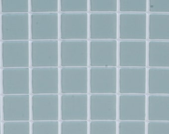 Puede incluir: Primer plano de una cuadrícula de baldosas cuadradas. Cada baldosa es de un color verde azulado suave y apagado, y están separadas por finas líneas de lechada blanca. Las baldosas crean un patrón repetitivo.
