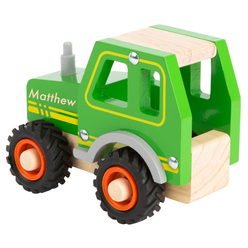 May include: Green wooden toy tractor with a name tag that says "Matthew" on the side. The tractor has a wooden cab with a removable roof and four wheels.