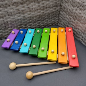Op de afbeelding: Een regenboogkleurig houten xylofoon met twee houten hamers. De xylofoon heeft acht toetsen en is gemaakt van verschillende soorten hout.