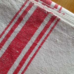 May include: White kitchen towel with red stripes. The towel is folded in half and the red stripes are visible on both sides.