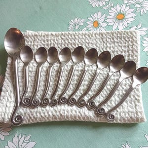 Ten small swirl coffee spoons plus a dessert spoon, steel, design, swirly, cutlery, French, moka, tea