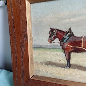 May include: Oil painting in a wooden frame depicting a brown horse with tack. The horse stands in a field under a cloudy sky. The painting has a vintage aesthetic, with visible brushstrokes and a warm color palette.
