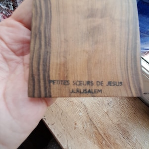 May include: A wooden plaque with the text "Petites Soeurs de Jesus Jerusalem" inscribed on it.