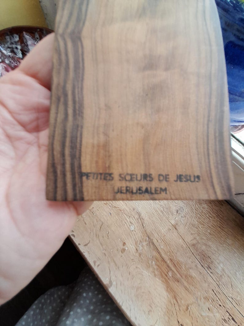 May include: A wooden plaque with the text "Petites Soeurs de Jesus Jerusalem" inscribed on it.