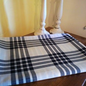 May include: A white and black plaid tablecloth with a folded edge. Two white candle holders with gold accents are in the background.