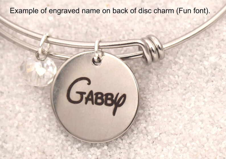 Pode incluir: Um bracelete de prata com um charme de disco de prata gravado com o nome "GABBY" em uma fonte divertida. O charme &eacute; preso ao bracelete com um anel de prata. Um charme de cristal transparente pendura do bracelete.