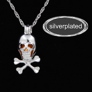 May include: Silver-plated skull and crossbones charm necklace. The charm is hollow and has a small opening on the top. The necklace is on a silver chain.