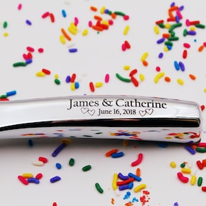 Op de afbeelding: Een zilveren ijslepel met de inscriptie "James & Catherine June 16, 2018" op het handvat.