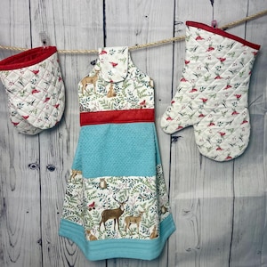 May include: A set of three kitchen towels with a woodland theme. The towels feature a red and white quilted design with a blue and white striped pattern. The towels are hanging on a clothesline.