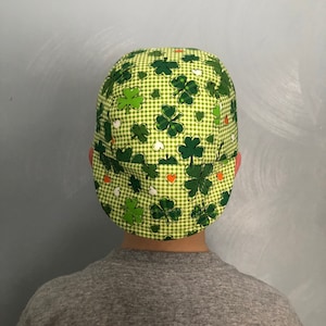 Puede incluir: Una gorra de b&eacute;isbol a cuadros verdes y blancos con un patr&oacute;n de tr&eacute;bol. La gorra tiene una visera verde y una corona blanca.
