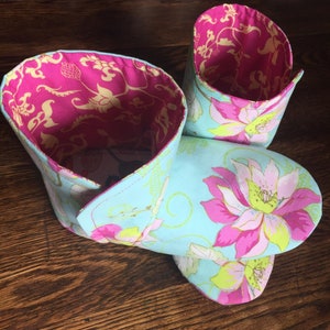 May include: A pair of blue and pink floral fabric slippers with a pink floral lining. The slippers are folded down to show the lining.