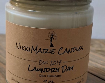 Peut inclure: Bougie en pot en verre transparent avec un couvercle argenté. L'étiquette marron porte l'inscription "Nikki Marie Candles, Laundry Day, Odor Eliminator". La bougie contient 255g de cire blanche crémeuse.