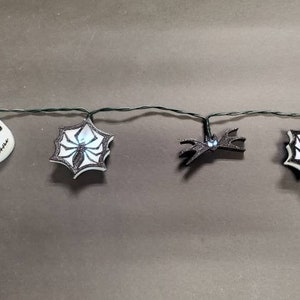 May include: A string of Halloween lights with white and black Jack Skellington and spider web designs.