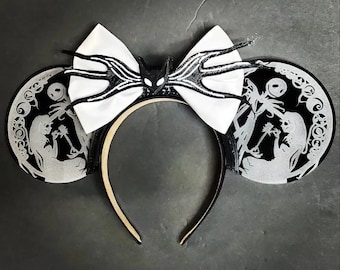 May include: Black and white mouse ears with a white bow featuring a black silhouette of Jack Skellington's head and arms. The ears are decorated with a silver glitter finish and feature a silhouette of Jack Skellington and Sally from the Nightmare Before Christmas.