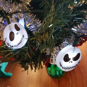 May include: White Christmas lights with Jack Skellington's face on them. The lights are strung on a green artificial Christmas tree.