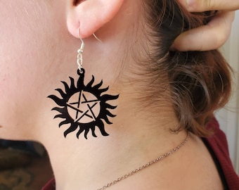 May include: Black dangle earrings with a pentagram inside a sun symbol.