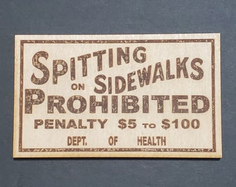 May include: A vintage wooden sign with the text "SPITTING ON SIDEWALKS PROHIBITED PENALTY $5 TO $100 DEPT. OF HEALTH". The sign has a distressed, worn look and is painted in brown.
