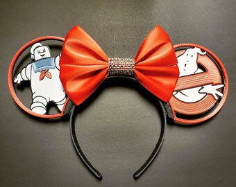 May include: Red satin bow headband with black ears featuring a white cartoon ghost and a white cartoon Stay Puft Marshmallow Man.