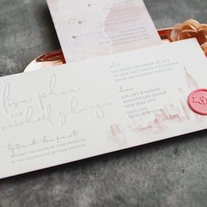 Invitación de boda impresa en tipografía: impresión tipográfica gris, silueta de horizonte en acuarela, sello de lacre rosa, mapa, sobre de vitela, forro de sobre, cordón gris.