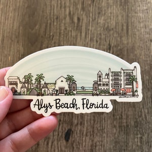 May include: Alys Beach, Florida sticker featuring a stylized illustration of buildings, palm trees, and a beach scene. The sticker has a white border and the text "Alys Beach, Florida" in a handwritten style font.
