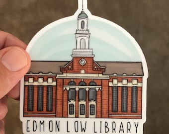 May include: A sticker featuring a detailed illustration of a brick building with a tall tower. The building has multiple windows and a light blue sky background. The text "EDMON LOW LIBRARY" is at the bottom.