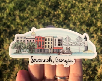 May include: A sticker featuring a watercolor illustration of Savannah, Georgia. The design includes buildings, a bridge, a lighthouse, and a riverboat. The text "Savannah, Georgia" is written in a script font.