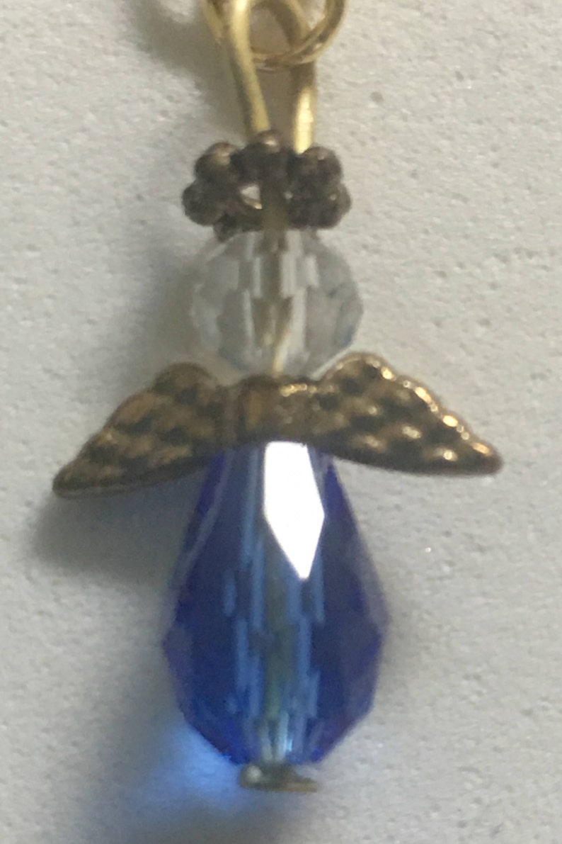 Op de afbeelding: Een gouden engelbedel met een blauw kristallen lichaam en gouden vleugels. De engel heeft een helder kristallen hoofd en een gouden kroon.