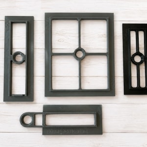 May include: A set of four rectangular dark gray and black plastic frames with internal grid structures and circular cutouts. The frames feature embossed text including 12x4, 10x10, and 20x4, with varying grid patterns and orientations for crafting.